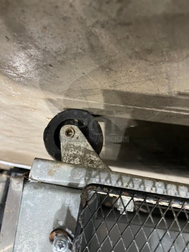 Stainless steel caster wheel beneath Sun Ice Model LUNST72-30 refrigerated prep table, showing metal frame and mesh detailing.