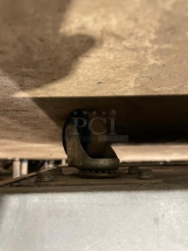 Close-up of a caster wheel on a Glastender FV48-XS(LR) stainless steel bar back cooler, showing wear.