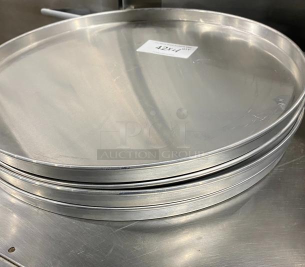 Four commercial aluminum round pizza pans stacked; durable, shiny surface. White tag labeled "42X4 QTY" visible.