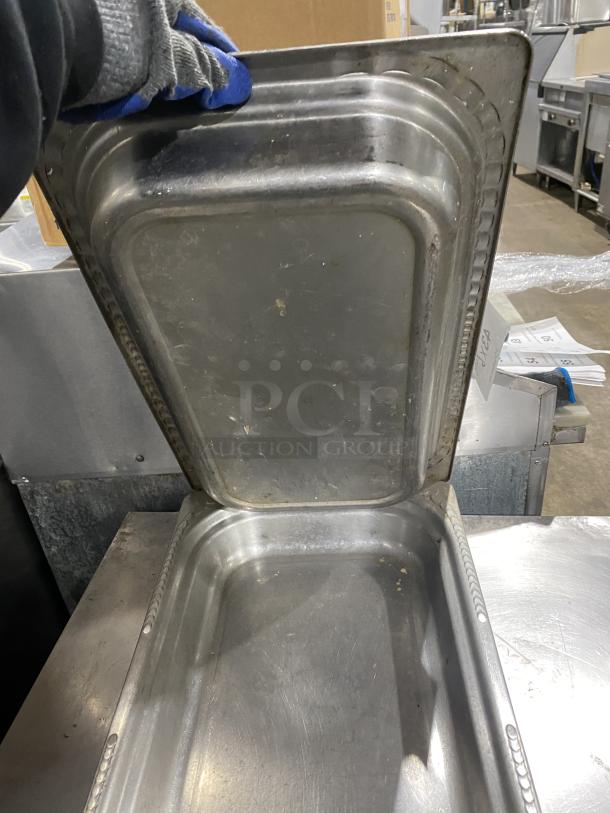 Commercial stainless steel stackable food serving trays, multiple trays shown. Sturdy and slightly worn, ideal for catering use.