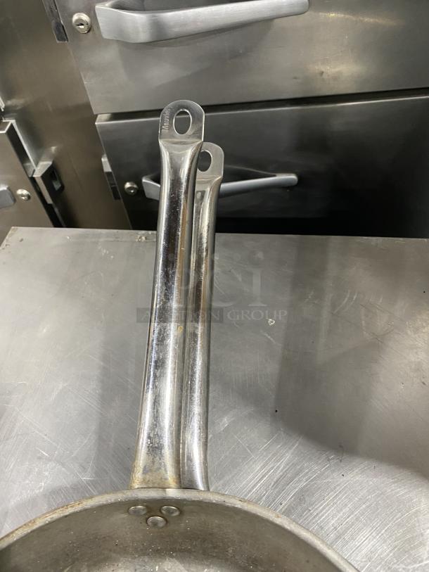 Commercial round frying pan with metal handle, visible wear, suitable for high-demand kitchens.