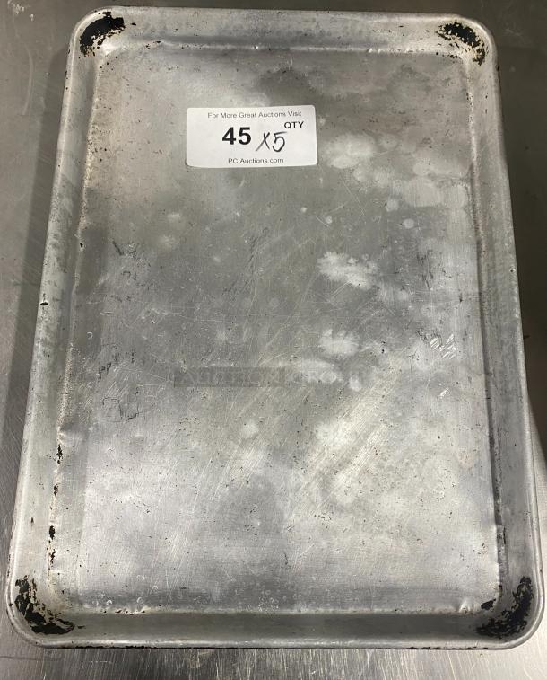 Commercial stainless steel full-size sheet pan, used condition, visible wear. Tag indicates quantity "5X".