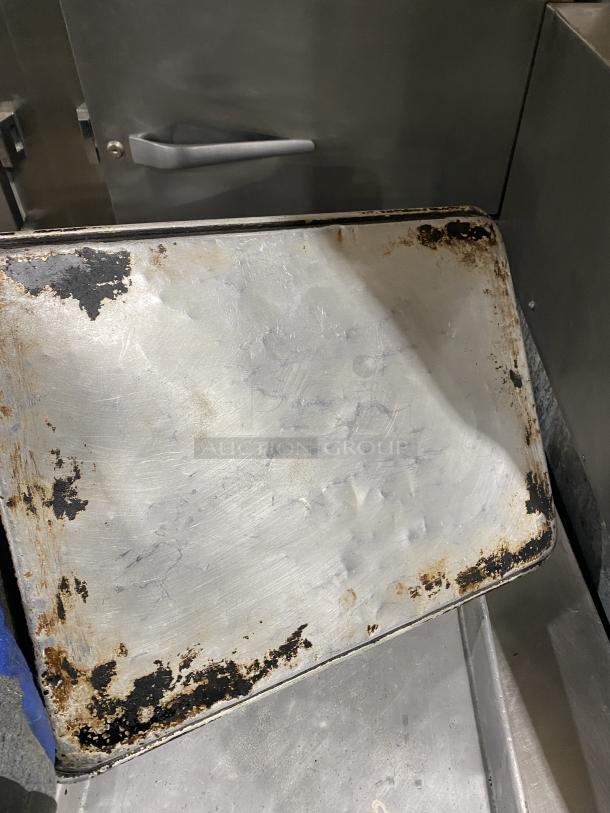 Commercial stainless steel full-size sheet pan with visible wear and charring. Durable for heavy-duty use.