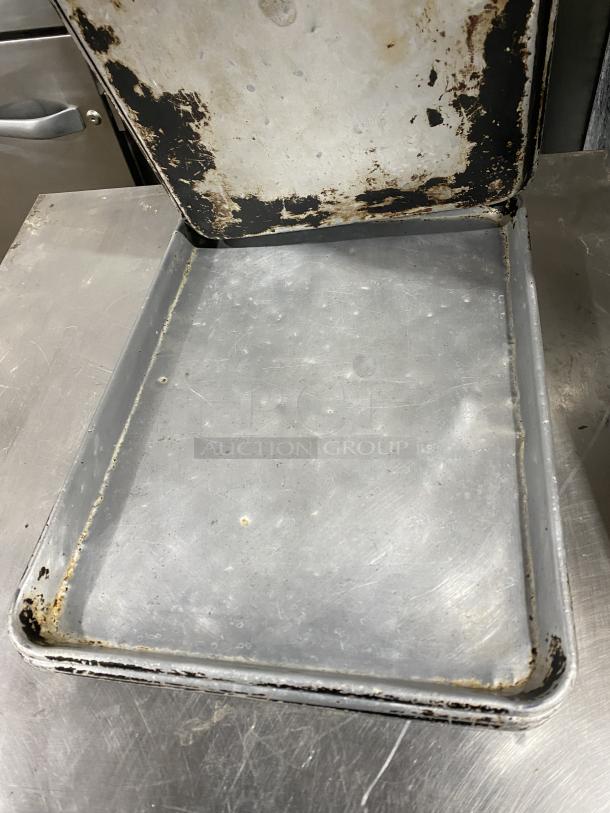 Commercial stainless steel full-size sheet pan, used condition with noticeable wear and discoloration, ideal for baking.