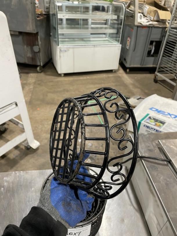 Commercial black round wired basket, ornate scroll design, used condition, approximately 9 inches in diameter.
