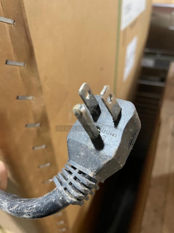 Close-up of the Arctic Air Commercial Freezer's power plug and cord against a cardboard background.