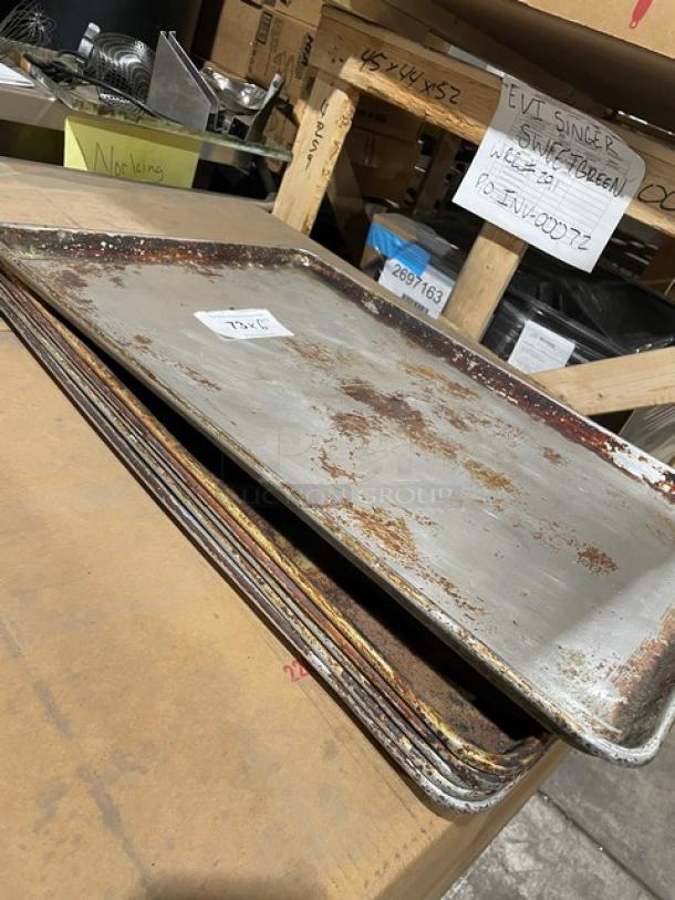 Stack of commercial aluminum full-size sheet pans, used condition with visible wear, bidding includes six pans.