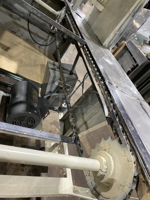 Commercial stainless steel dough sheeter machine, showing motor, chains, and metal components; used condition.