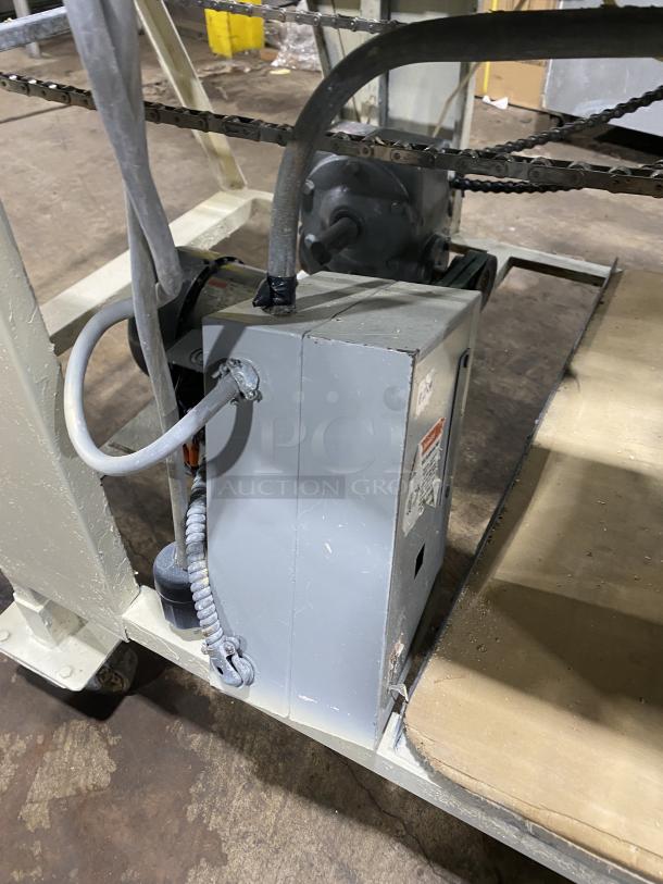 Commercial stainless steel dough sheeter machine with motor and chain mechanism; used condition with visible wiring and components.