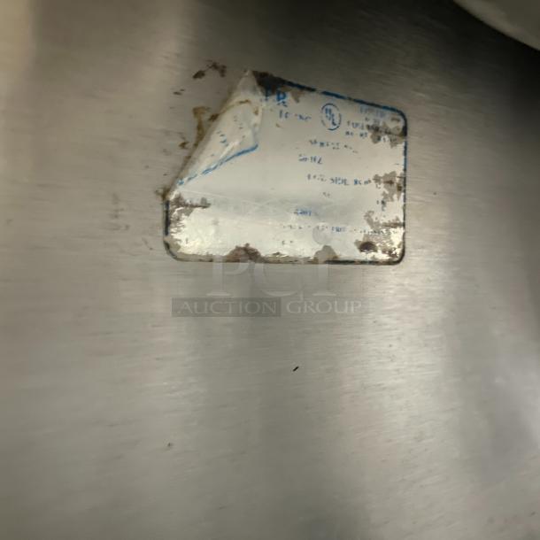 Stainless steel refrigerated prep table with cutting board, poly-coated rack, casters. Worn label indicating usage marks.