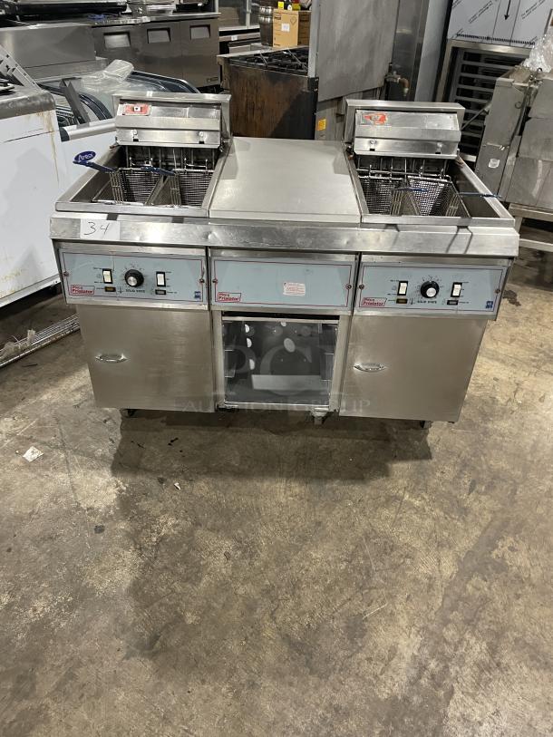 Pitco Frialator 2-Bay Deep Fat Fryer System with basket hanger, center pan cabinet, backsplash, casters; stainless steel.