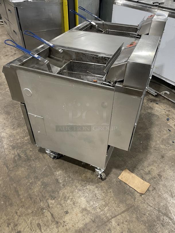 Pitco Frialator Series 2-bay deep fat fryer system with center enclosed pan, back splash, basket hanger, and casters.