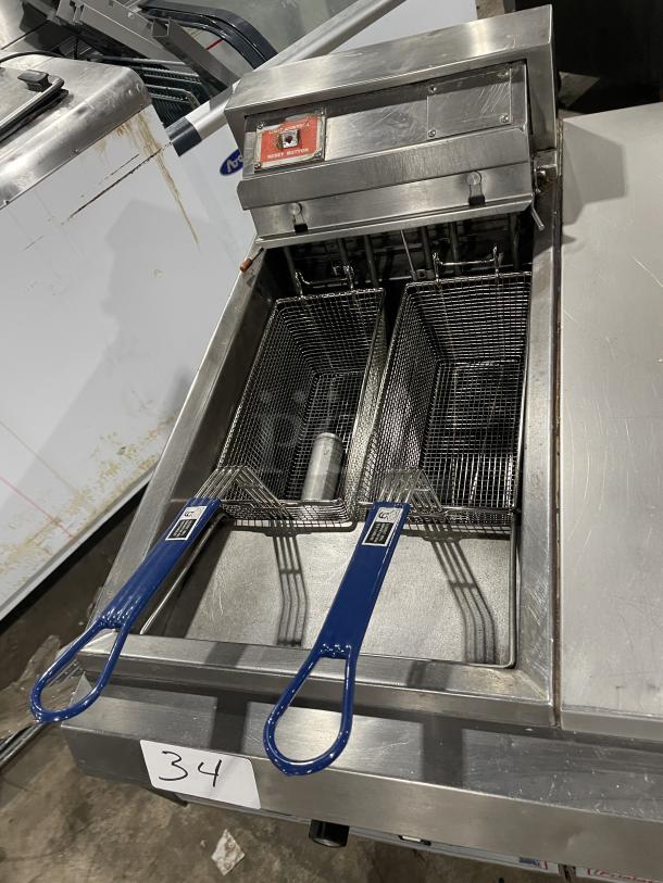 Pitco Frialator commercial 2-bay deep fat fryer system with center pan cabinet, backsplash, and basket hanger, on casters.