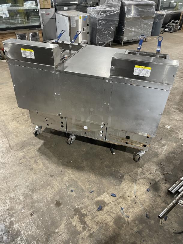 Pitco Frialator stainless steel 2-bay deep fat fryer with enclosed pan cabinet, backsplash, basket hanger, and fry basket on casters.