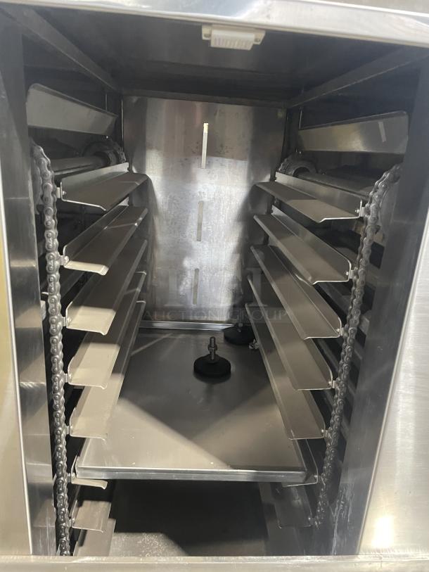 Aksar commercial tray wrapping machine, floor style, heavy duty, interior view showing stainless steel trays and chain mechanism.