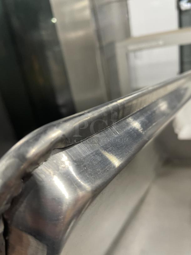 Brand new Advance Tabco full-size baking sheet pans, close-up of edge detail, stainless steel, pristine condition, 12-piece set.