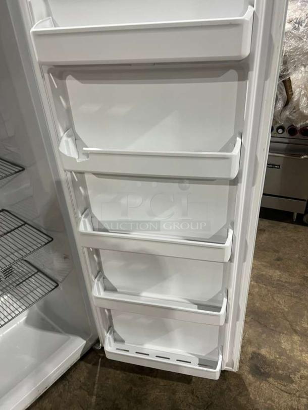 Frigidaire upright freezer, Model FFFU16F2VW, with door storage bins, wire shelves, and a clean white interior.