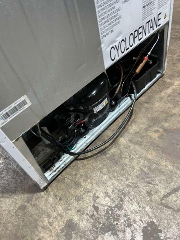 Frigidaire upright freezer model FFFU16F2VW, showing rear view with compressor and electrical components exposed.