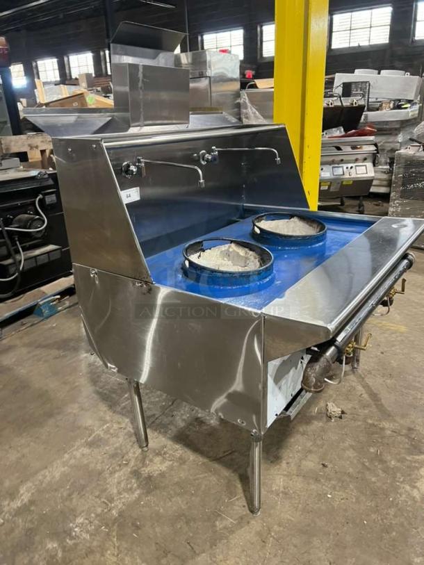 Stainless steel gas-powered dual wok range with high BTU output, built-in faucets, on legs, like new condition.