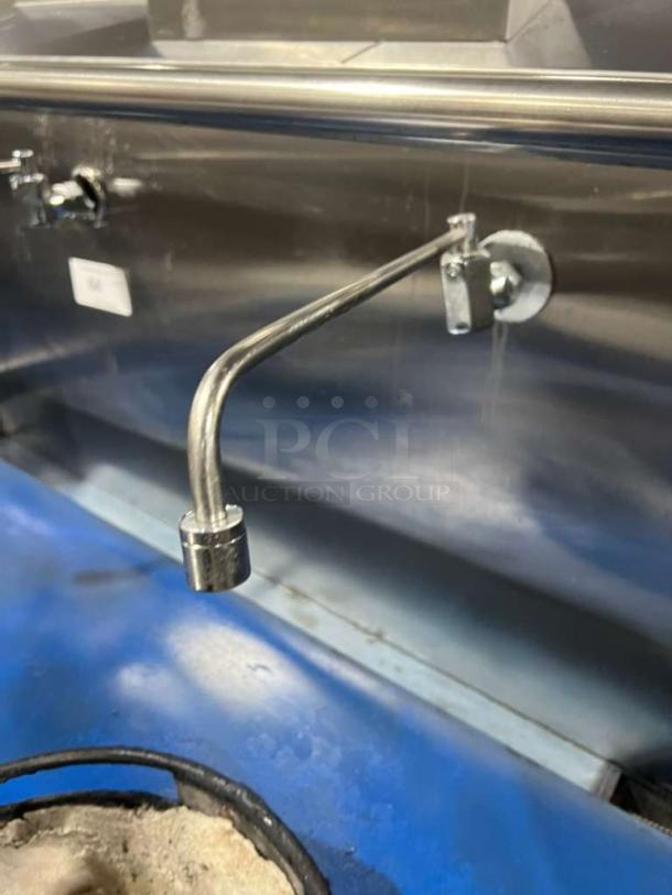 All stainless steel gas-powered dual wok range with built-in faucet, shown in like-new condition.