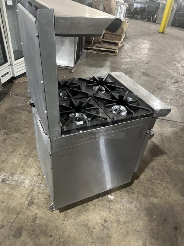 American Range stainless steel gas-powered 4-burner range/oven combo with backsplash, salamander shelf, and wired oven rack on casters.