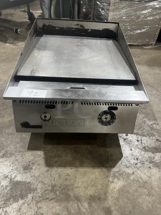 Commercial stainless steel gas-powered countertop flat griddle with back and side splash, adjustable legs, well-used condition, tag 92.