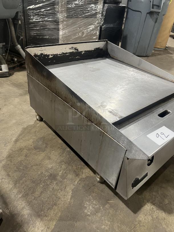 Commercial stainless steel gas-powered countertop flat griddle with back and side splash, on legs. Used condition.
