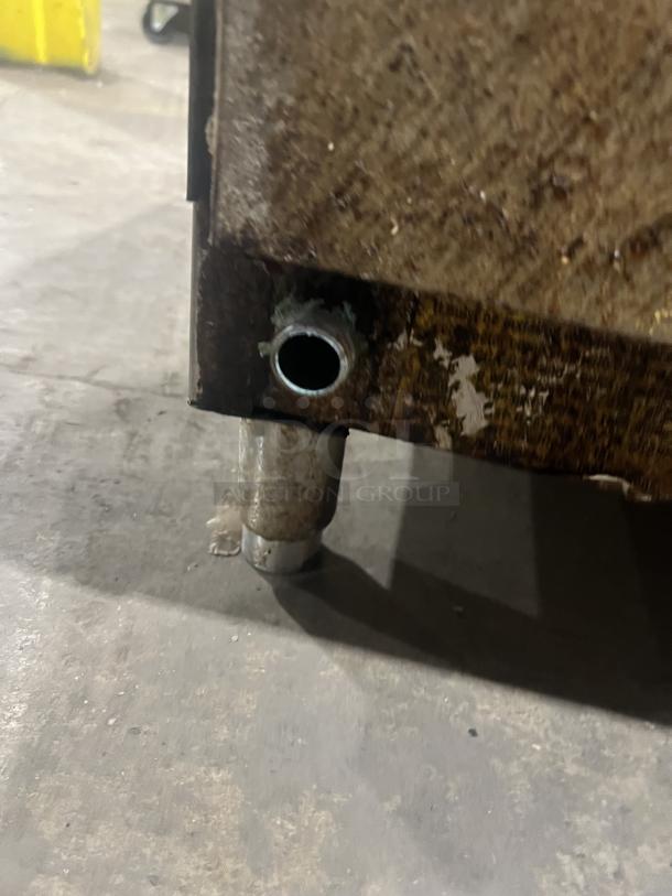 Commercial stainless steel gas griddle corner view. Shows leg detail, indicated wear. Designed with back and side splash.