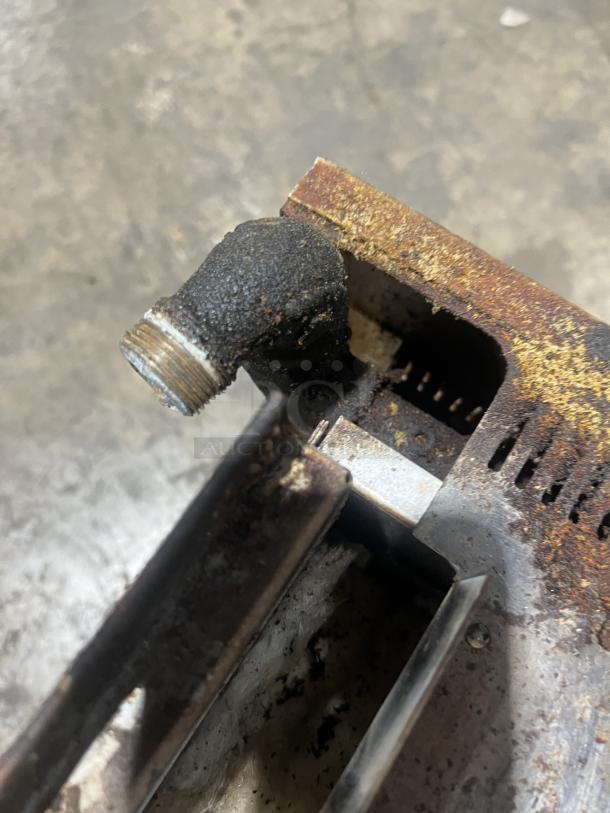 Commercial stainless steel gas salamander broiler close-up, showing signs of wear and rust on metal fittings.