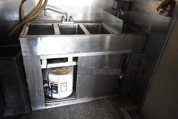 Stainless steel triple sink in Burger King corporate spec mobile kitchen trailer, including plumbing and storage underneath.