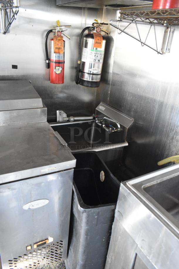 Interior view of a 2019 mobile kitchen trailer with fire extinguishers, sink, and stainless steel equipment.