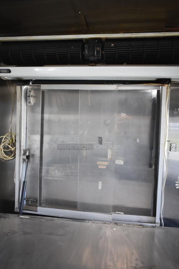 2019 Quality Cargo mobile kitchen trailer interior with grease hood. Features metal fittings and coiled cables visible.