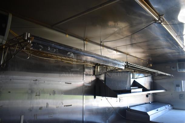 2019 Quality Cargo 8.5' x 24' mobile kitchen trailer interior with grease hood, stainless steel surfaces, shelving, and wiring.