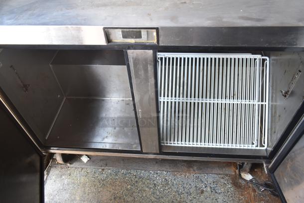 Interior view of 2019 mobile kitchen trailer showing stainless steel refrigerator space and wire rack, part of the cooking setup.