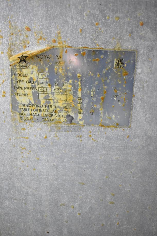 Metal surface with a rusted, partially legible label showing gas specifications and installation details.