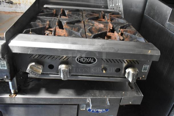 Royal stovetop in mobile kitchen trailer, featuring four burners with control knobs, moderate wear and grease buildup visible.