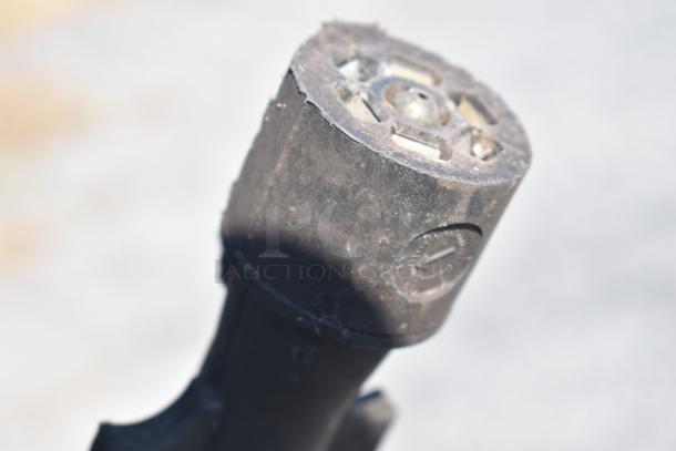 A close-up of a dusty metal object, possibly part of a larger mechanical or industrial setup. The surface shows wear from use.