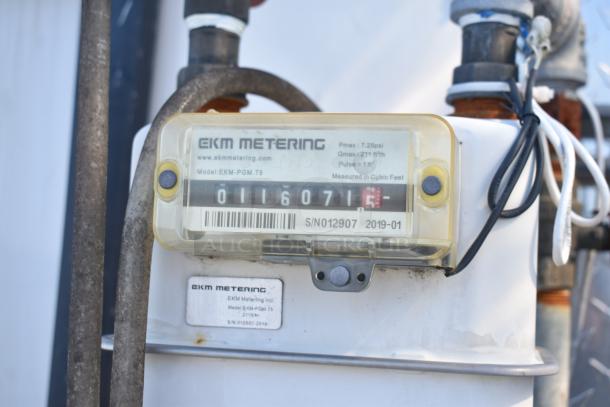 An EKM metering device model EKM-PGM.75 on a mobile kitchen trailer, showing metering details and serial number S/N012907.