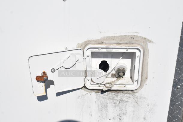 Exterior view of a 2019 Quality Cargo mobile kitchen trailer's service panel, showing wear and rust.