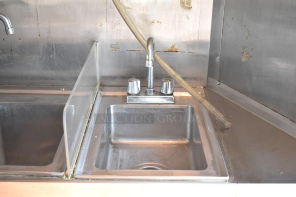 Stainless steel sink with dual faucets in a 2019 Quality Cargo mobile kitchen trailer, used condition.