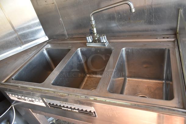Stainless steel triple sink in Burger King mobile kitchen trailer with labeled "Water Line" marking.