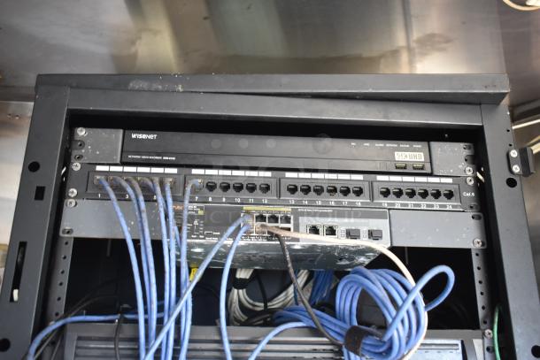 Network equipment inside a 2019 Quality Cargo mobile kitchen trailer, featuring Visenet video recorder and Aruba network switch, connected by multiple cables.