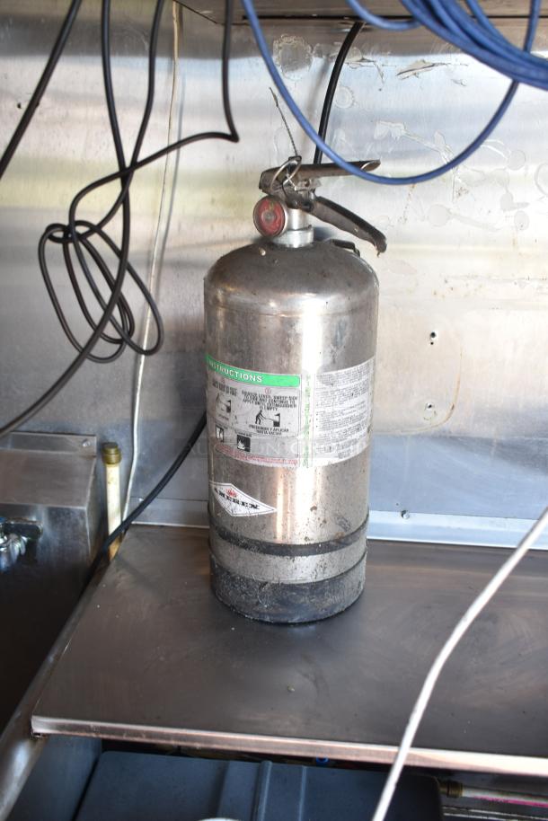 Fire extinguisher inside 2019 Quality Cargo mobile kitchen trailer. Marked instructions visible. Part of Burger King corporate spec.