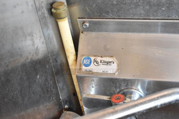 NSF-certified Klinger’s Trading, Inc. label on stainless steel surface, model MCS1, next to a grease hood component.