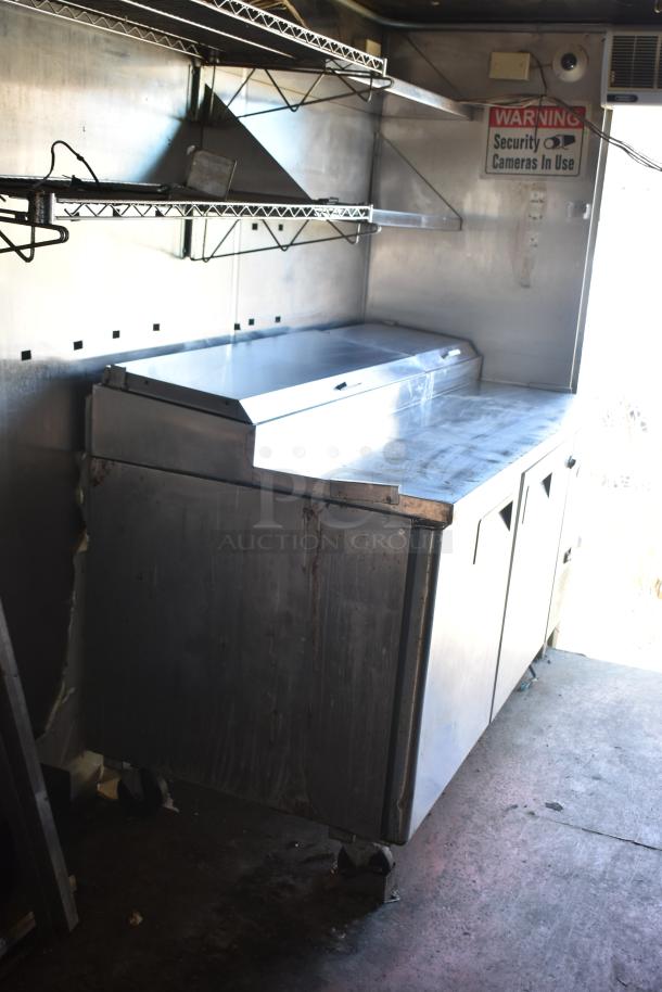 2019 Quality Cargo 8.5' x 24' mobile kitchen trailer interior with stainless steel shelving and work area. Sign reads "Security Cameras In Use."