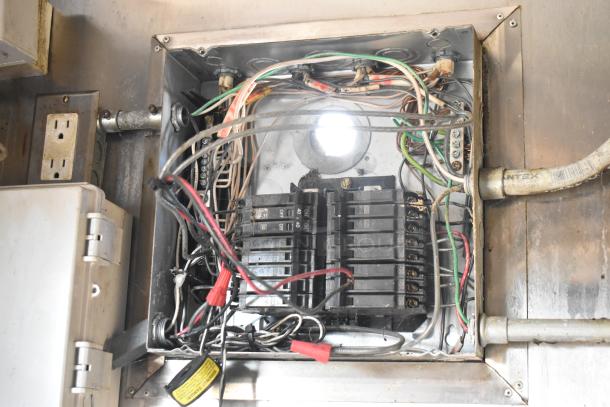 Electrical panel with wires and circuit breakers inside the 2019 Quality Cargo kitchen trailer. Condition unknown.