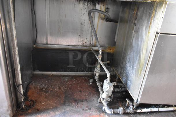 Interior view of a 2019 Quality Cargo mobile kitchen trailer. Visible grease hood and utility piping, showing signs of use.