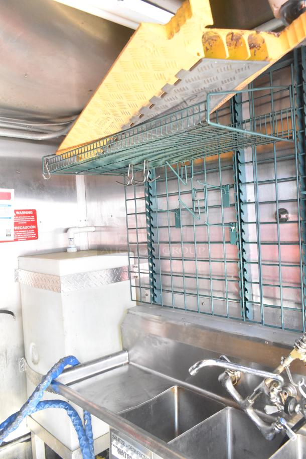2020 Diamond Cargo mobile kitchen trailer interior with wire racks, stainless steel triple sink, and safety warnings.