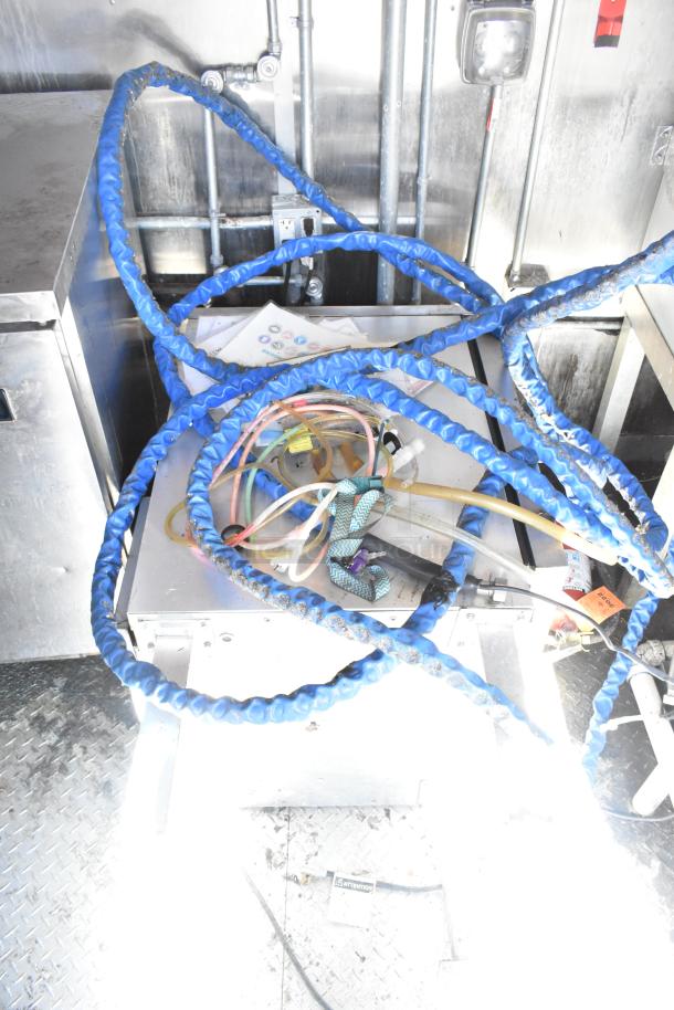 2020 Diamond Cargo mobile kitchen trailer interior, showing pipes and cables. Features industrial utility setup.