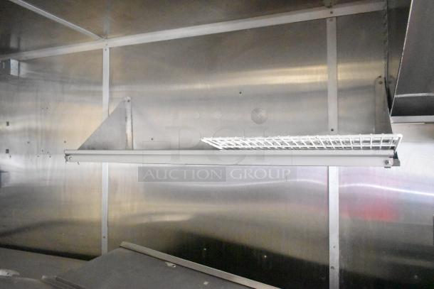 Interior view of a 2020 Diamond Cargo mobile kitchen trailer, featuring stainless steel walls and a wire rack shelf.